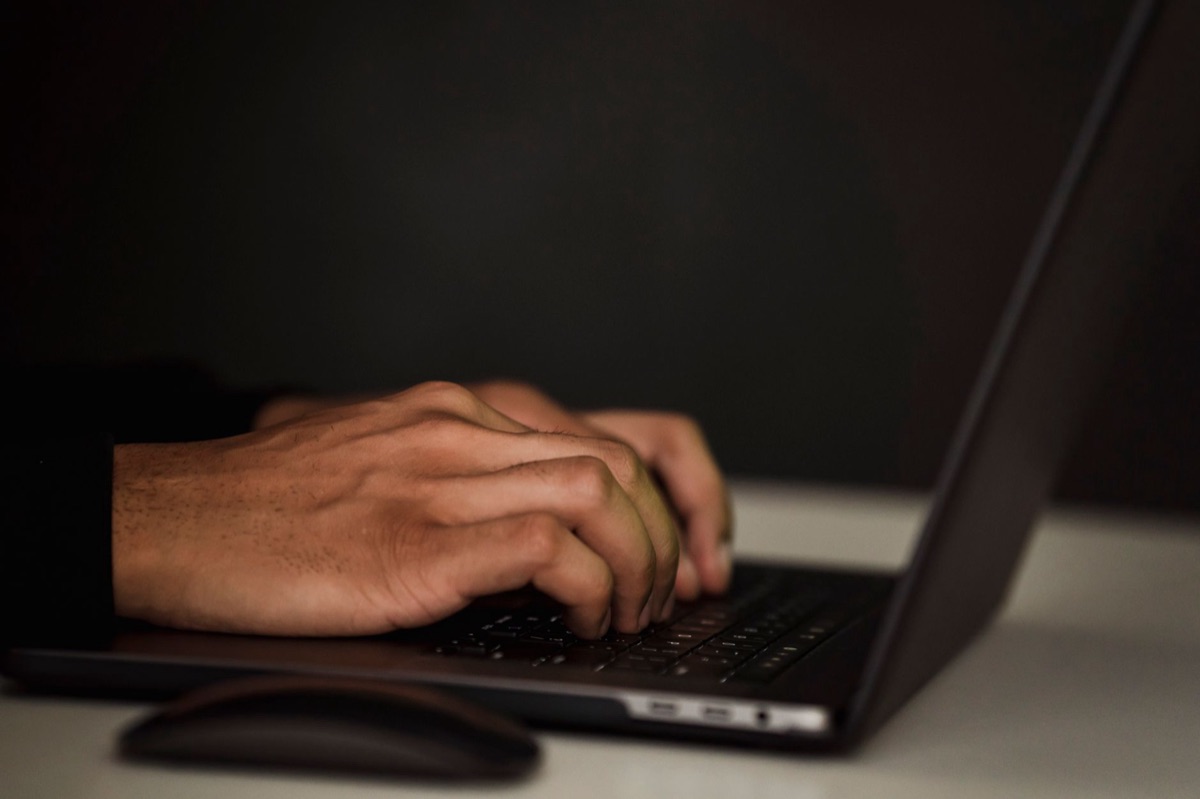 Close-up de mãos digitando um assunto de e-mail em um laptop para atrair cliques.