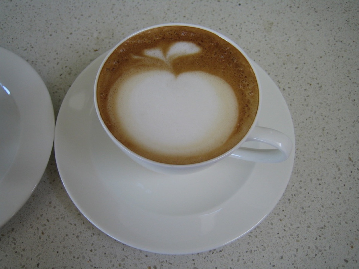 Milchschaum wird in eine Kaffeetasse gegossen